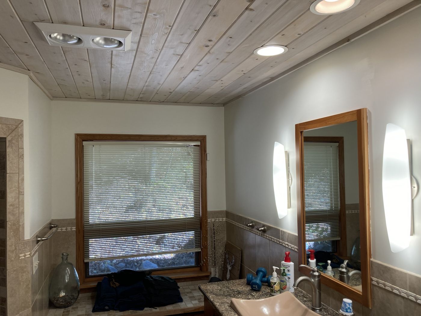Bathroom walls above the tile under a whitewashed pine ceiling