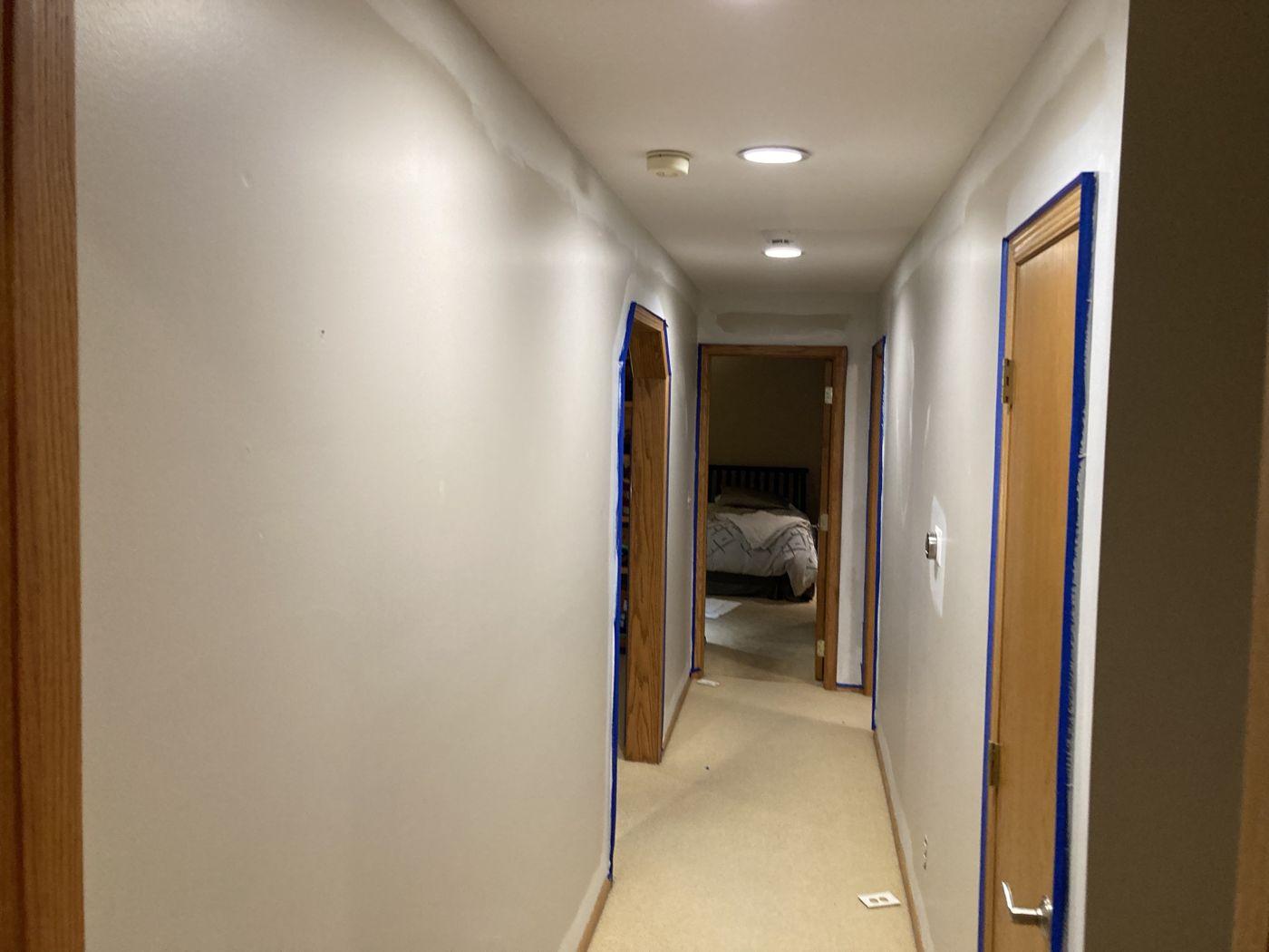 Hallway with blue tape on every door casing and patched spots